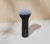 INIKA Organic Kabuki brush standing upright on a light background with a black handle and dense rounded bristles fading to lighter tips.