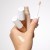Hand holding three PureMatch Liquid Concealers with applicator and shade swatches on the skin.