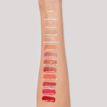 Vertical swatches of Jane Iredale lip gloss shades on a forearm from light to deeper tones.