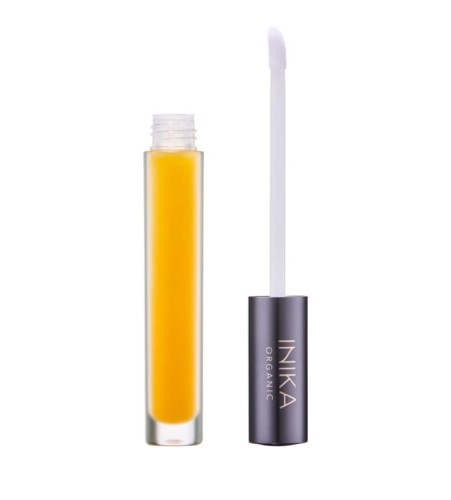 Slim clear glass bottle filled with intense yellow lip serum or oil, with applicator removed beside it.
