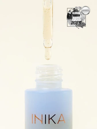 Bottle of INIKA Organic Hyaluronic Hydration Complex with a pipette above the open neck and clear serum visible as a lightweight hydrating texture.