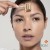 Close-up of a woman using Cosmetic Gold Roll-CIT with movement guide marks on the forehead.