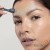 Woman using Focus-CIT on the forehead with graphic movement marks.