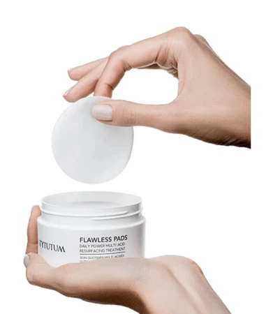Hands reaching for a single INSTYTUTUM Flawless Pad from the jar.