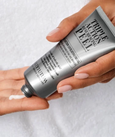 Hand squeezing white INSTYTUTUM Triple Action Resurfacing Peel onto the palm from a silver tube.