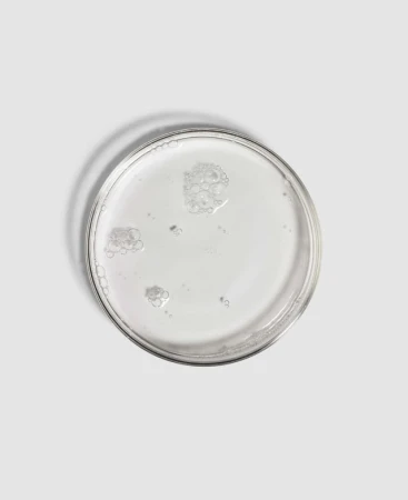 Clear ENVIRON Alpha Hydroxy Toner liquid sample poured into a shallow glass dish on a light background.