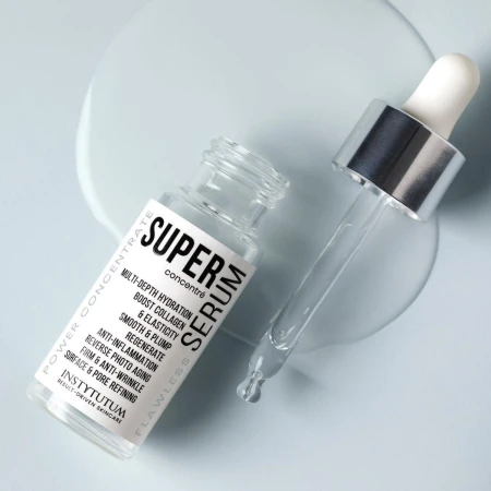 Open INSTYTUTUM Super Serum bottle and glass pipette on a pale blue surface with serum spilled beside it.