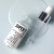 Open INSTYTUTUM Super Serum bottle and glass pipette on a pale blue surface with serum spilled beside it.