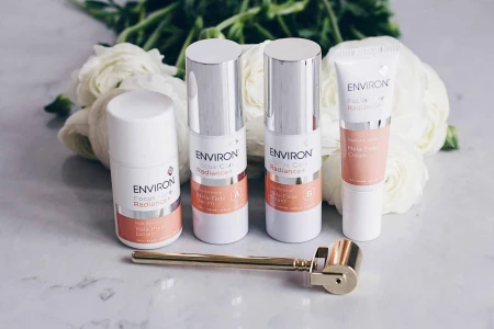 Environ Focus Care Radiance products on a marble surface with flowers and a gold Roll-CIT in front.