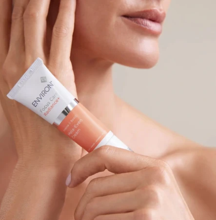 Close-up of hands holding an ENVIRON C-Boost Mela-Even Cream tube.