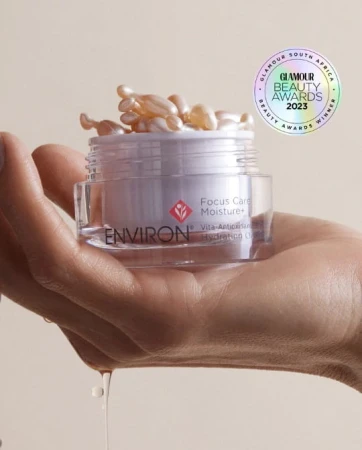 Hand holding an open jar of capsules with oil flowing from opened capsules and Glamour Beauty Award logo above.