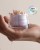 Hand holding an open jar of capsules with oil flowing from opened capsules and Glamour Beauty Award logo above.