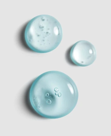 Close-up of blue gel serum droplets with bubbles on a grey background.