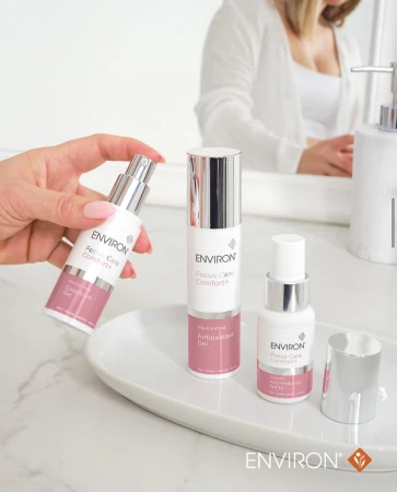 Hand holding ENVIRON Colostrum Gel among Environ Focus Care Comfort+ products.