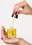 Hands holding INSTYTUTUM Powerful Retin Oil bottle and dropper with yellow oil against a light background.