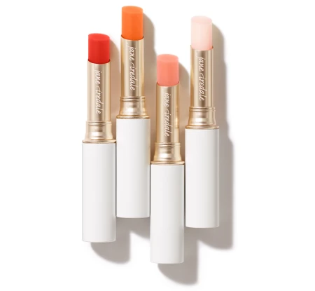 Four Jane Iredale Just Kissed Lip and Cheek Stain sticks in white tubes with gold details.