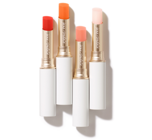 Four Jane Iredale Just Kissed Lip and Cheek Stain sticks in white tubes with gold details.