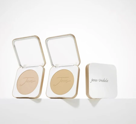 Jane Iredale refillable compacts in gold and white with minimalist design and powder inside.