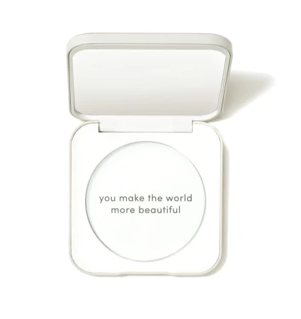 White Jane Iredale refillable compact with front text “you make the world more beautiful” and mirror visible under the lid.