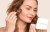 Model applying Jane Iredale PurePressed Base with a brush while holding a white refillable compact.