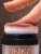 Close-up of the INIKA Organic Puff Pot sponge applicator touching a fingertip with soft rosy powder.