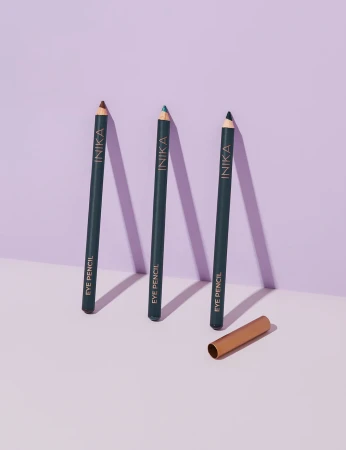 Three INIKA Organic Eye Pencil shades standing upright with a gold cap on a pale background.