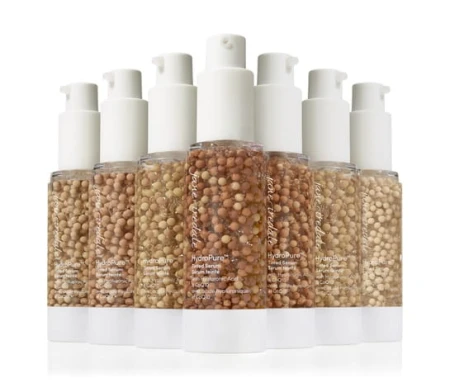 Jane Iredale HydroPure Tinted Serum bottles in multiple shades with white pump dispensers.
