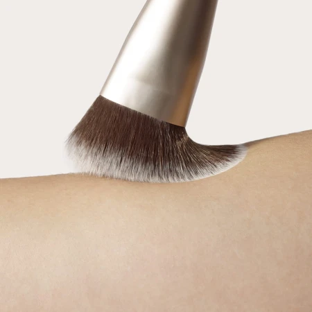 Dense soft makeup brush gliding over skin for smooth blending.
