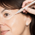 Application of Jane Iredale Active Light concealer under the eye with a brush-pen applicator.