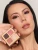 Model holding INIKA Organic Quad Eyeshadow Palette FLOWERS beside warm brown, burgundy and beige eye makeup.