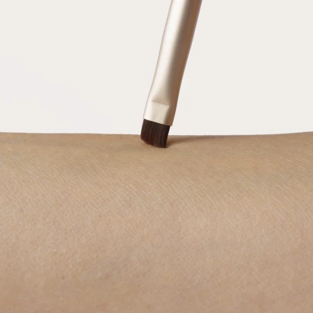 Angled precision brush tip applied to skin for eyes, brows or eyeliner detail.