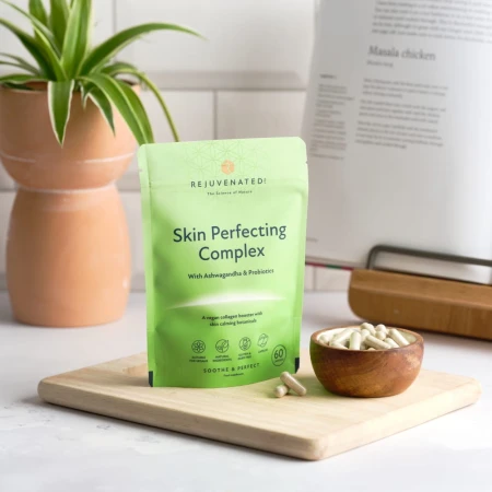 Rejuvenated Skin Perfecting Complex green pack with capsules in a wooden bowl.