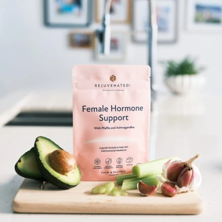 Rejuvenated Female Hormone Support pink pack on a kitchen counter with avocado, celery and garlic.