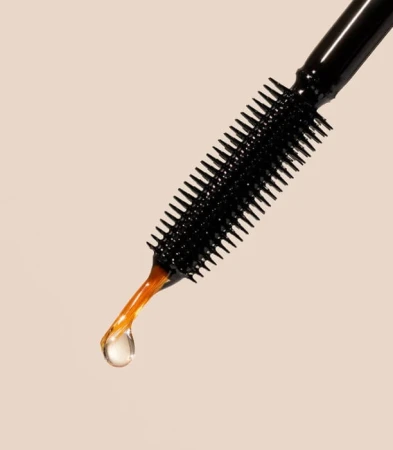 Close-up of an INIKA serum applicator brush with a drop of clear amber serum