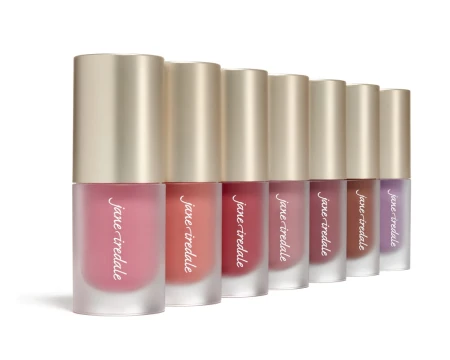 Several Jane Iredale ColorLuxe Liquid Blush tubes with golden caps in shades from nude pink to deeper tones.