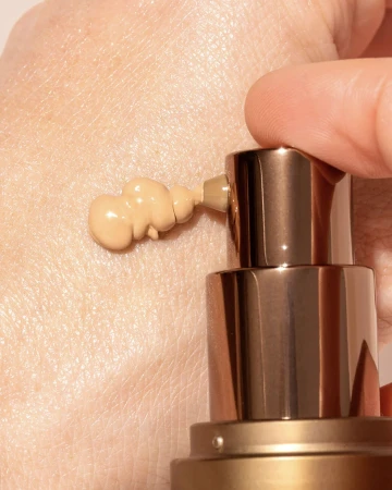 INIKA Organic BB Cream being dispensed from the pump onto the hand, showing its light creamy texture and natural shade.