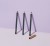 Three INIKA Eye Pencil eyeliners standing upright on a light background with a soft violet tone. Each has a dark barrel and a different colored tip with a gold cap nearby.